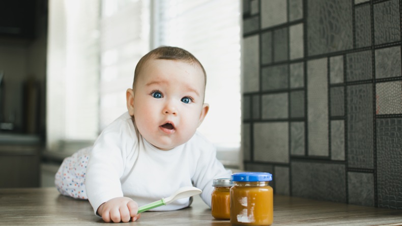 baby crawling with spoon and baby food jars