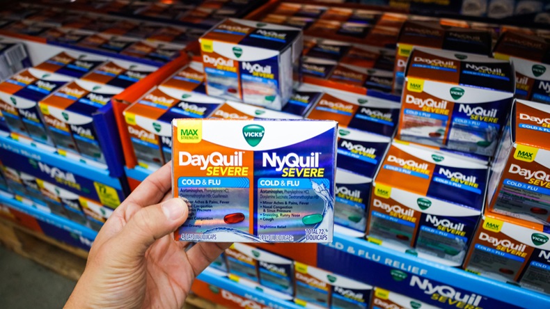 A hand holds a combo pack of Vicks DayQuil Severe and NyQuil Severe, on display at a local big box grocery store.