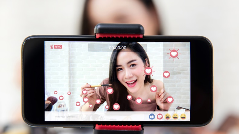 Asian woman professional beauty vlogger or blogger live broadcasting cosmetic makeup tutorial viral video clip by smartphone sharing on social media - Image 