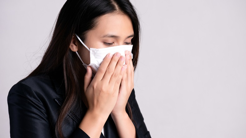 Close up of a businesswoman in a suit wearing Protective face mask and cough, get ready for Coronavirus and pm 2.5 fighting against on gray background.
