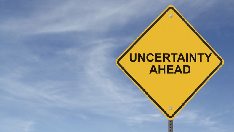 "Uncertainty Ahead” sign on a background of blue sky with clouds