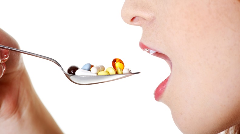 Closeup on teen caucasian girl`s open mouth taking pills from spoon. - Image 
