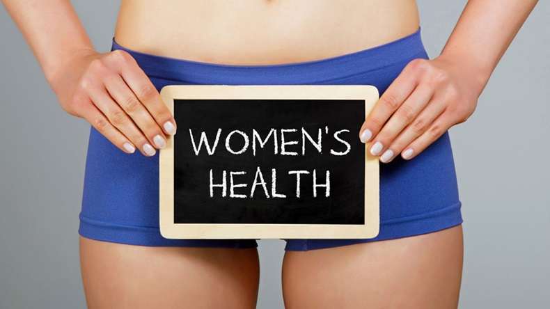 Women's health concept. Woman holds a small chalkboard with "Women's health" inscription