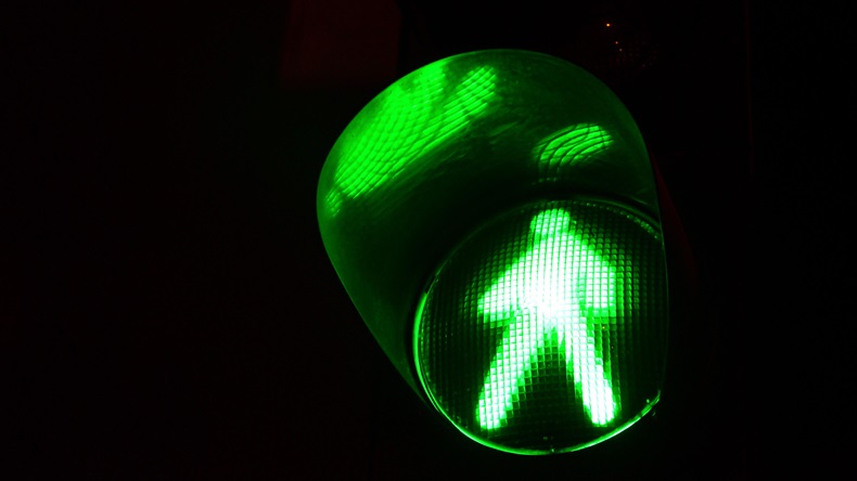 Night photo of a traffic light for pedestrians, which lights up in green.