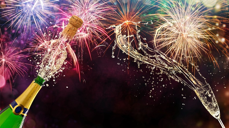 Bottle of champagne with glass over fireworks background. Celebration concept, free space for text