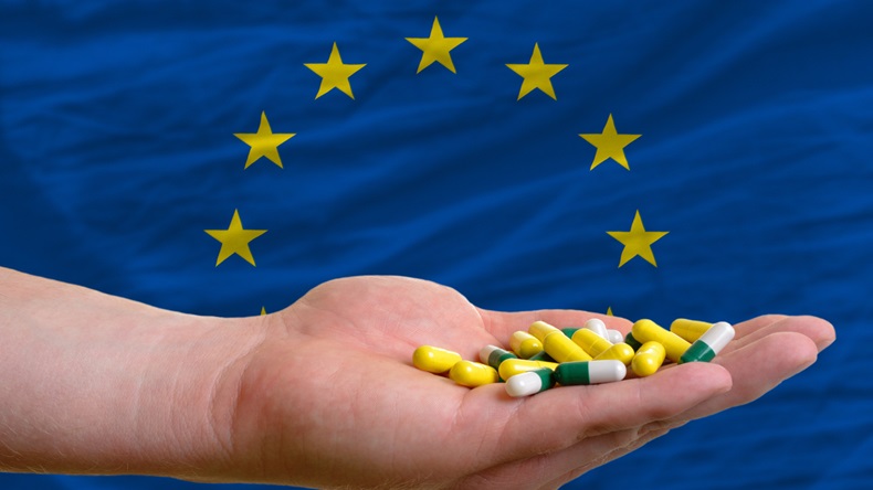 man holding capsules in front of complete wavy national flag of europe symbolizing health, medicine, cure, vitamines and healthy life