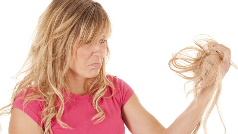 A woman has pulled out a handful of hair and is sad.