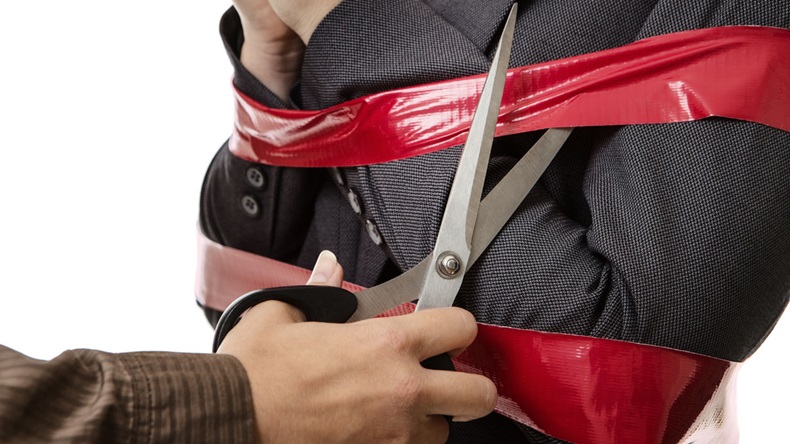 Business woman caught up in red tape being cut free with scissors