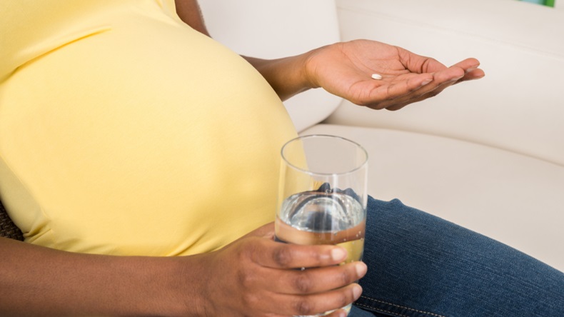 Close-up Of Pregnant Woman Holding Medicine With Glass Of Water At Home - Image 